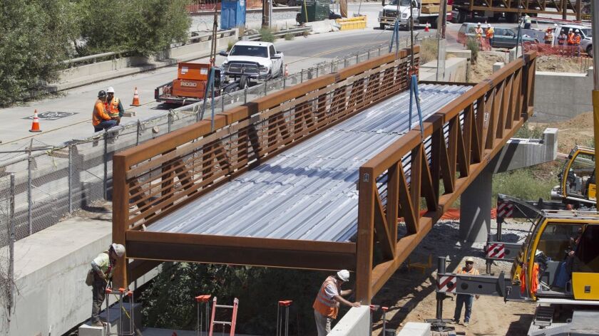Crews gently placed a 140 foot long, 64-ton steel section of the new Rose Creek Bikeway bridge in place on Wednesday. The bridge, for pedestrians and cyclists, will be a signature part of the 2.3 mile section of bikeway that SANDAG is building as part of the Coastal Rail Trail.