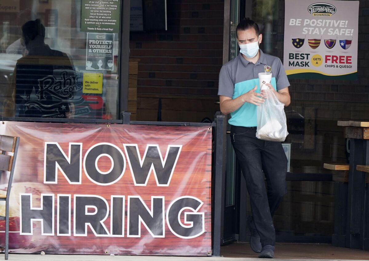 A customer wearing a face mask passes a "now hiring" sign leaving a Richardson, Texas, restaurant with takeout on Sept. 2.