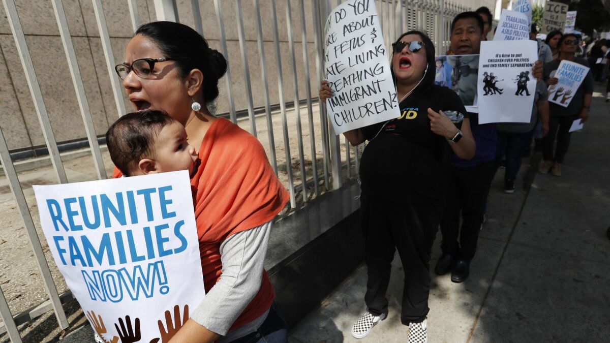 Angelia Garcia, left, of Los Angeles, holding her 4 month old baby Amada, marches with others outside the Federal Building on Aliso St. in downtown Los Angeles to protest against the way families are being separated at the border.
