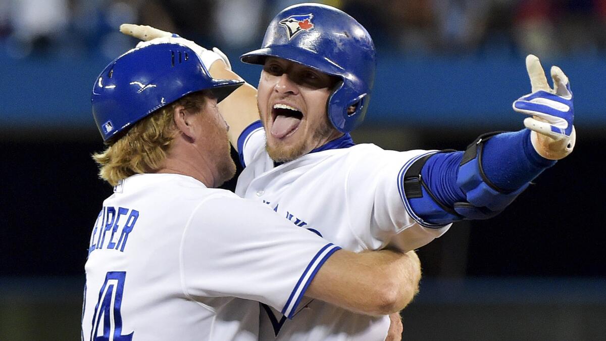Blue Jays third baseman Josh Donaldson is embraced by first base coach Tim Leiper after delivering the game-winning hit in the 11th inning against the Royals on July 31 in Toronto.