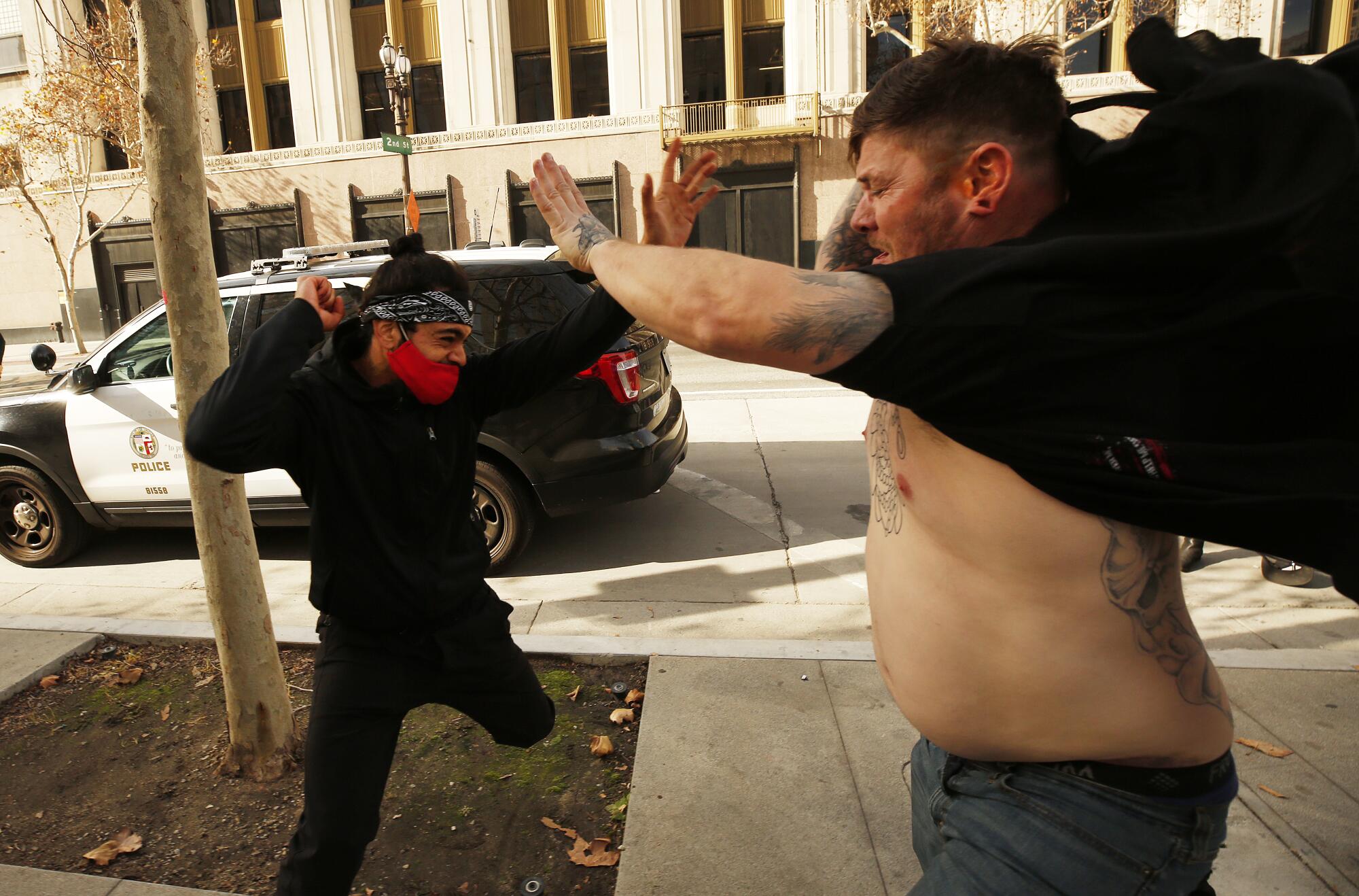 An anti-Trump protestor, left, and a pro-Trump demonstrator exchange blows after they rallied outside Los Angeles City Hall.