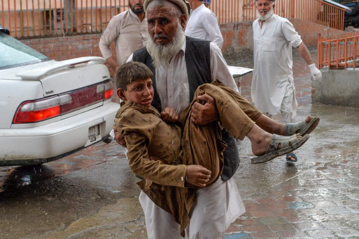 A volunteer carries an injured youth to a hospital