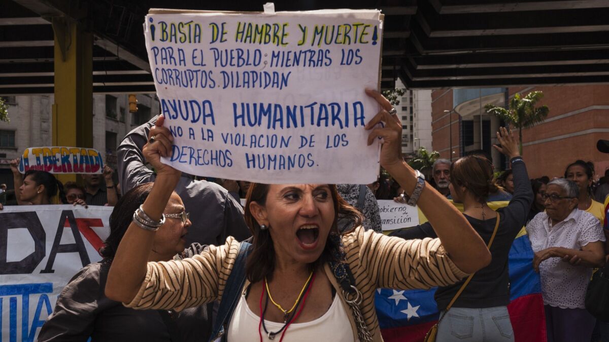People gather in Caracas, Venezuela, to support opposition leader Juan Guaido on Jan. 30, 2019. The sign reads: "Enough with hunger and death! For the people while the corrupt squander. Humanitarian aid. No to the violation of human rights."