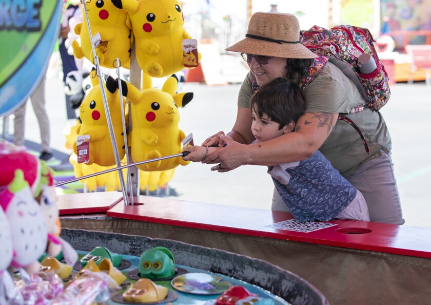 Kristie Shapiro helps her son Rhodry play a carnival game on opening day of the OC Fair Friday.