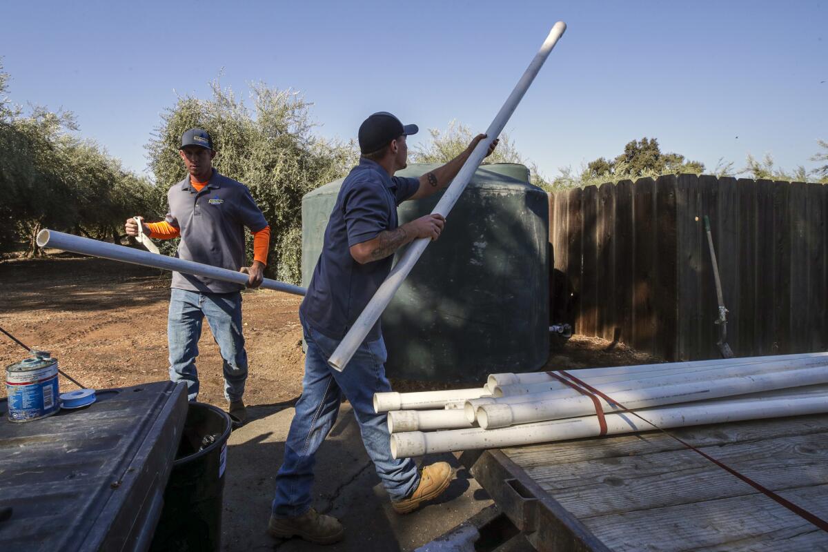 Two men install a water tank