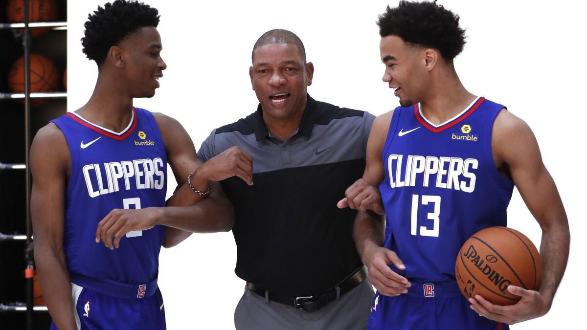 Clippers coach Doc Rivers jostles for position as he prepares to pose for a photo with rookie guards Shai Gilgeous-Alexander (2) and Jerome Robinson (13) during media day.