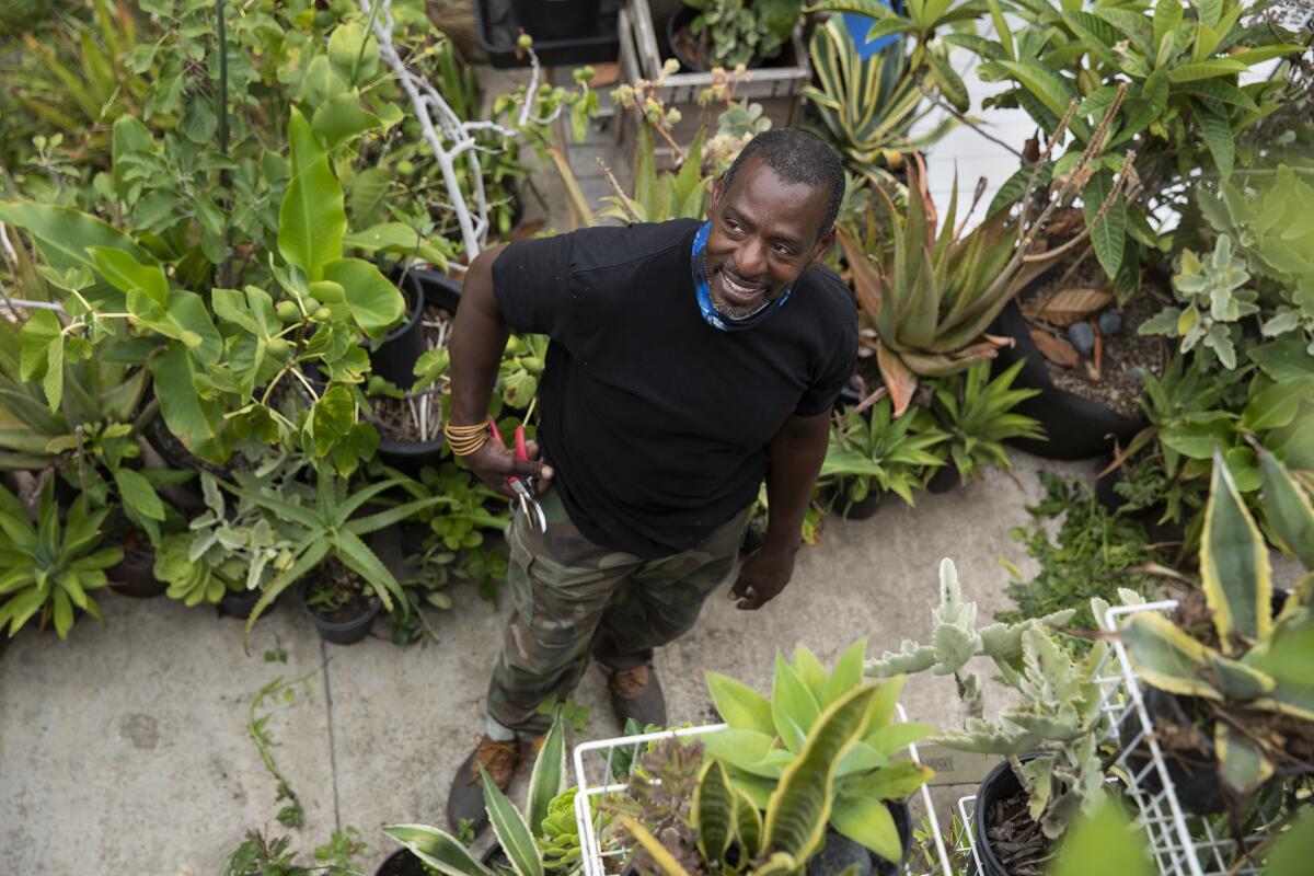 Ron Finley smiles in his garden surrounded by pots of succulents. 