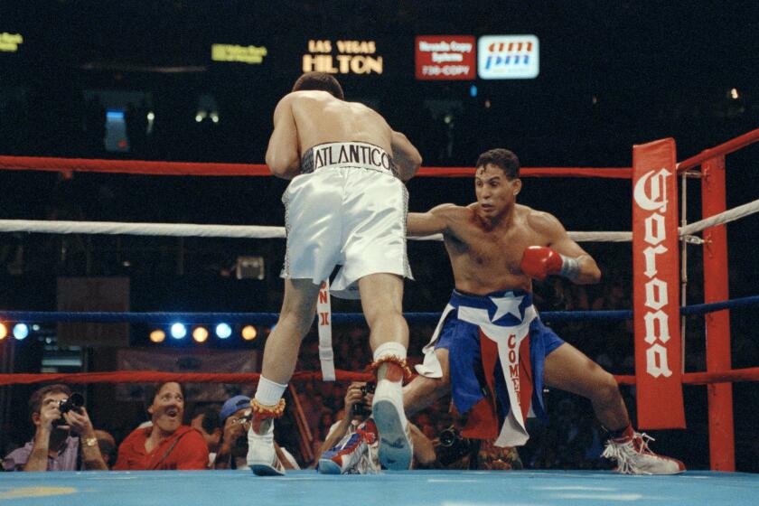 Challenger Hector Camacho gets down low in the corner while trying to avoid the charge of champion Julio Cesar Chavez.