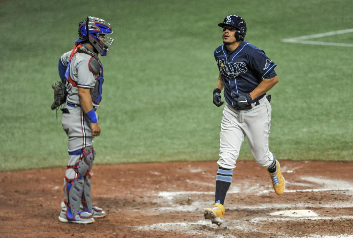 Texas Rangers catcher Jose Trevino watches as Tampa Bay Rays' Willy Adames, right, scores on a solo home run off Rangers Taylor Hearn during the eighth inning of a baseball game Monday, April 12, 2021, in St. Petersburg, Fla. (AP Photo/Steve Nesius)