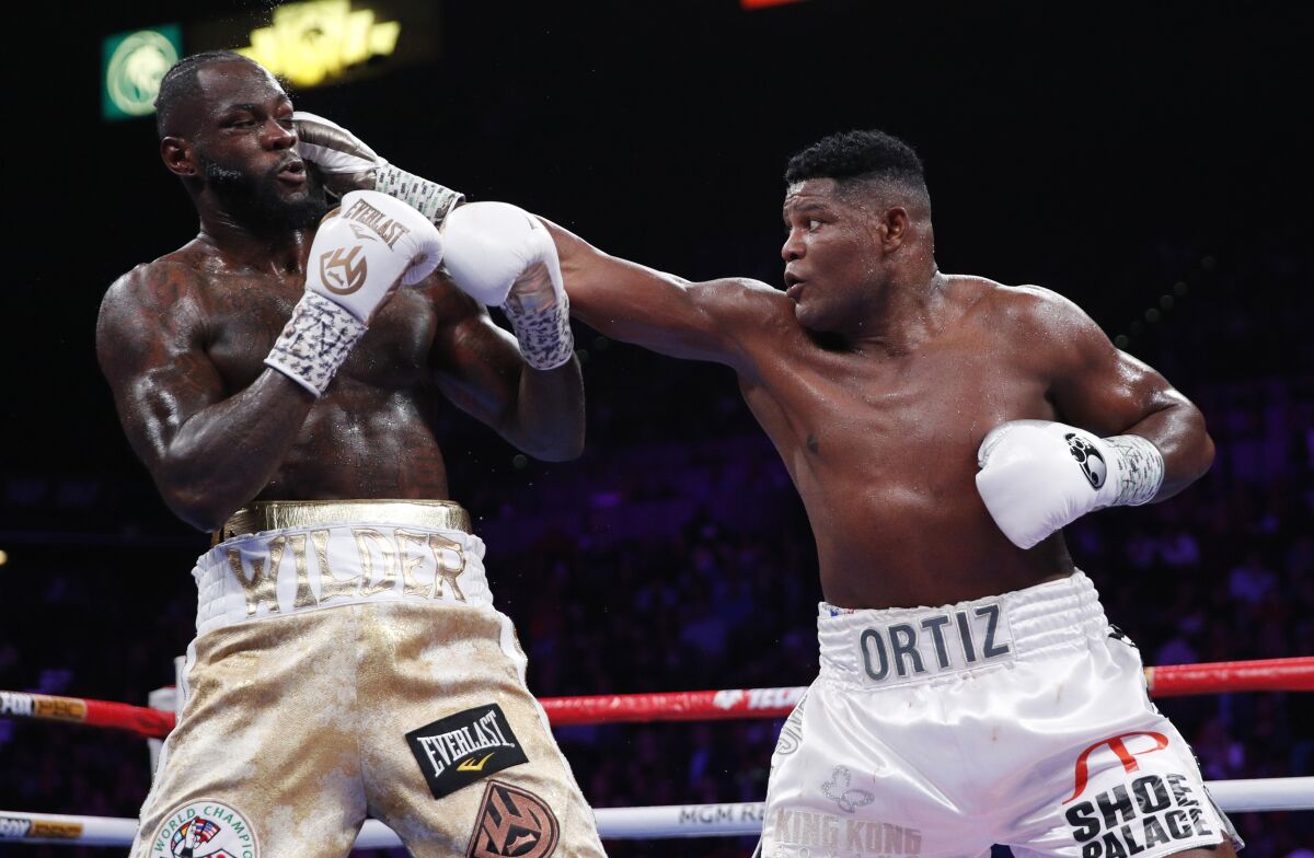 Luis Ortiz hits Deontay Wilder during the WBC heavyweight title boxing match Saturday.