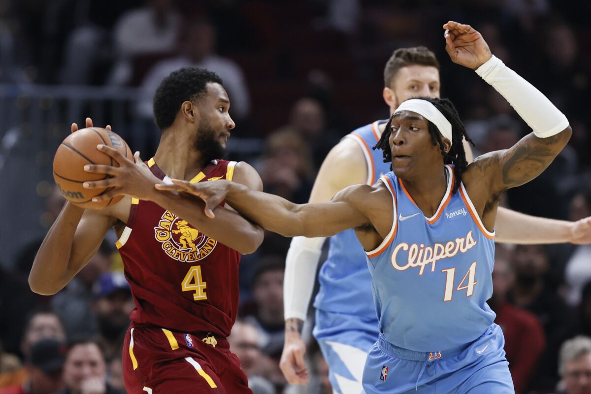 Los Angeles Clippers' Terance Mann (14) defends against Cleveland Cavaliers' Evan Mobley (4) during the first half of an NBA basketball game, Monday, March 14, 2022, in Cleveland. (AP Photo/Ron Schwane)