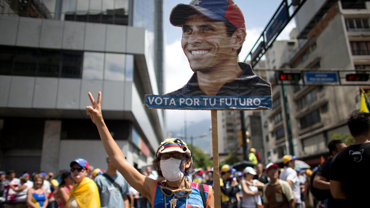 A woman carrying an image of Venezuelan opposition leader Henrique Capriles joins thousands protesting against the government of President Nicolas Maduro on Saturday in Caracas.