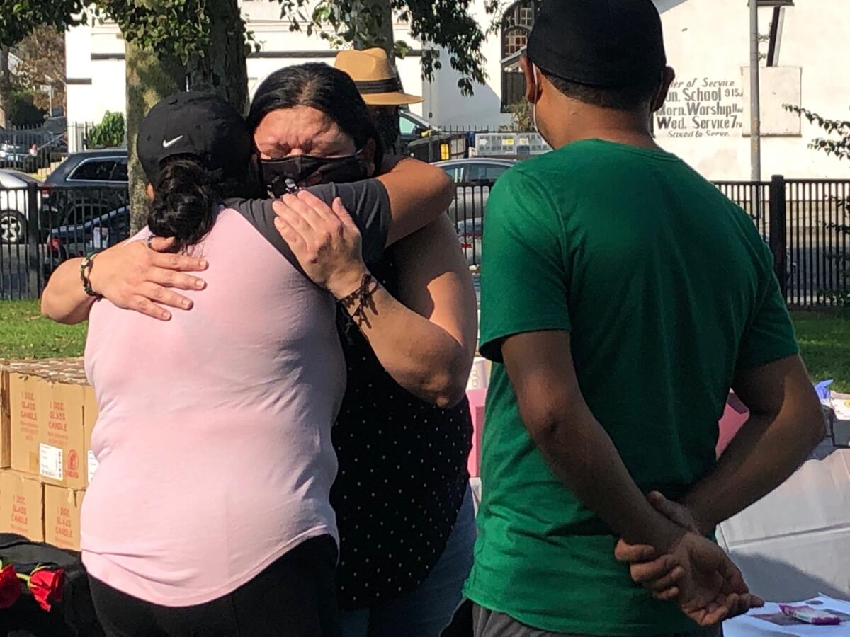 Yajaira Hernández es consolada por una persona durante la reunión comunitaria realizada en un parque de Los Ángeles.