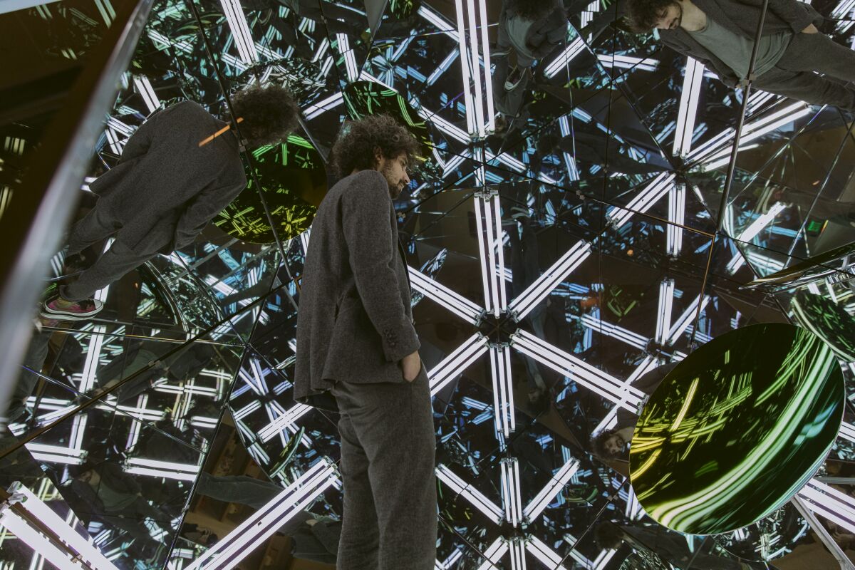 A man surrounded by lights and mirrors 