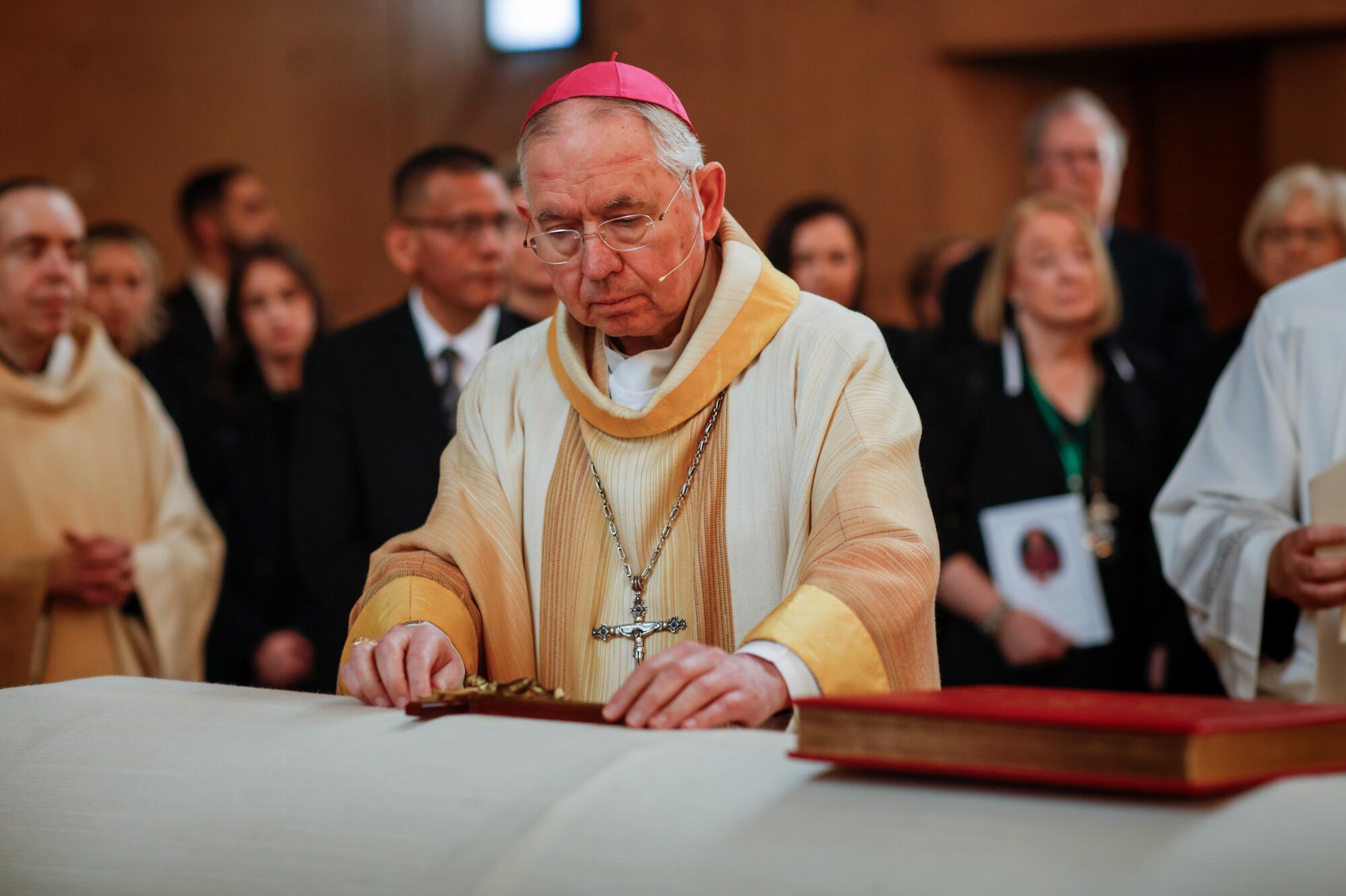 Archbishop Jose H. Gomez places Christian symbols on the coffin