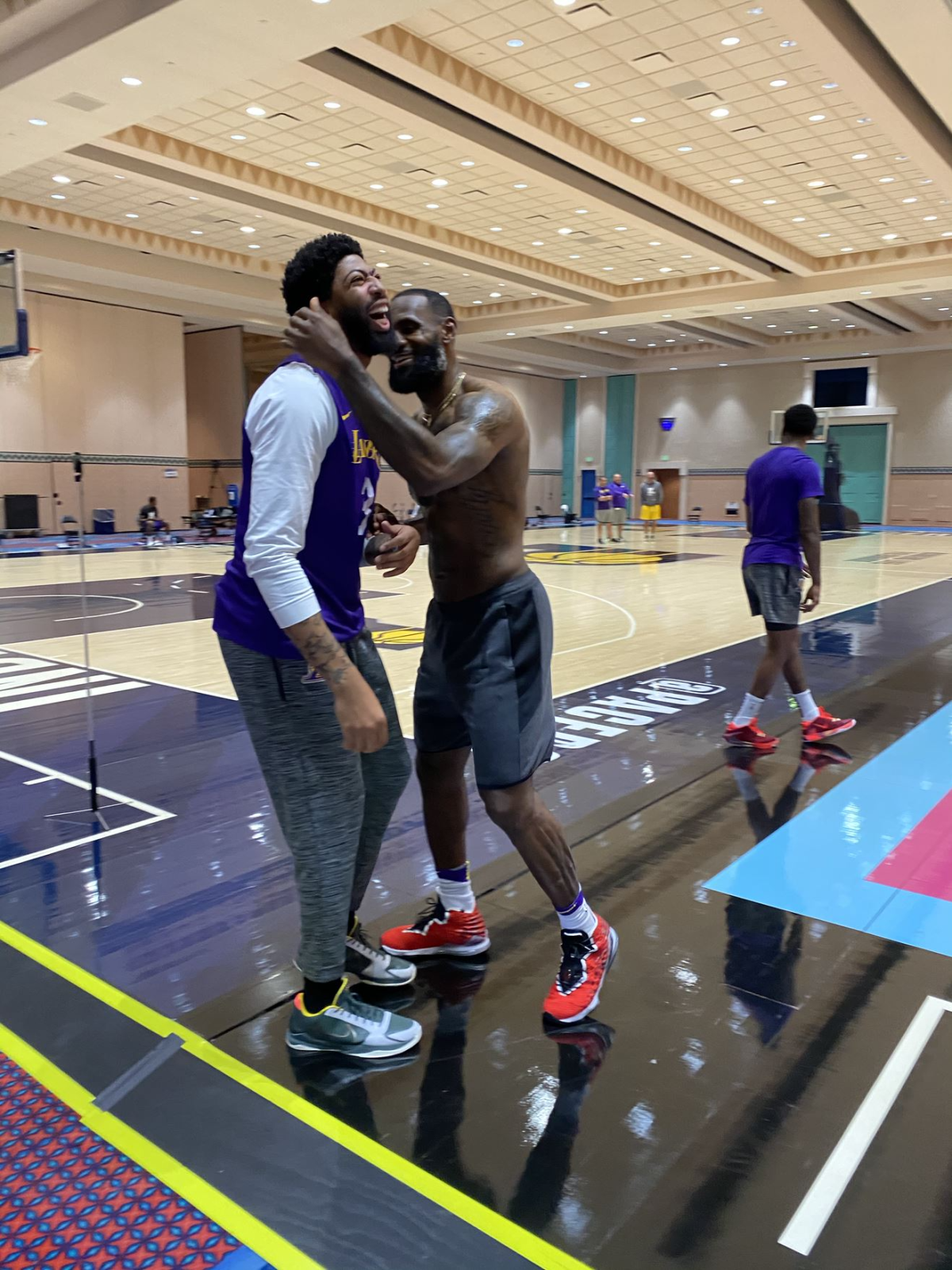 Anthony Davis, a la izquierda, de los Lakers, y LeBron James se ríen durante una sesión de práctica en Orlando.