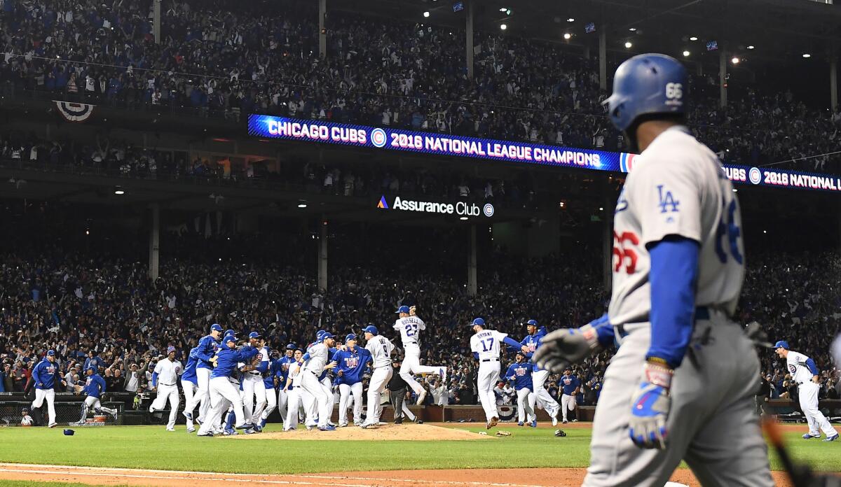 Dodgers outfielder Yasiel Puig walks off the field as Cubs players celebrate winning the National League Championship Series .