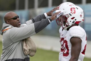 U.S. college Stanford's football players Bryce Love, right, and Cameron Scarlett get instructions from running backs coach Ron Gould, left, before running through a drill as the team trains ahead of the season opening game against Rice in Sydney, Thursday Aug. 24, 2017. The game will be played on Sunday. (AP Photo/Rick Rycroft)