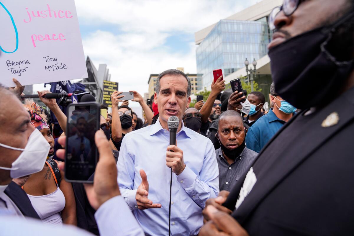 Mayor Eric Garcetti uses a microphone to speak to protesters outside Los Angeles City Hall