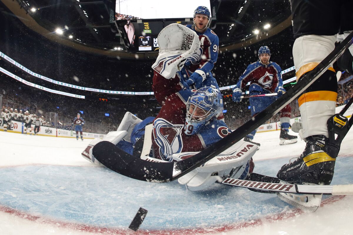 In this photo shot with a wide angle lens, Colorado Avalanche goaltender Pavel Francouz looks back to see the puck on the goal line but the play was ruled no goal as the goal had come off its moorings before the puck crossed the line during the second period of an NHL hockey game against the Boston Bruins Saturday, Dec. 3, 2022, in Boston. (AP Photo/Winslow Townson)