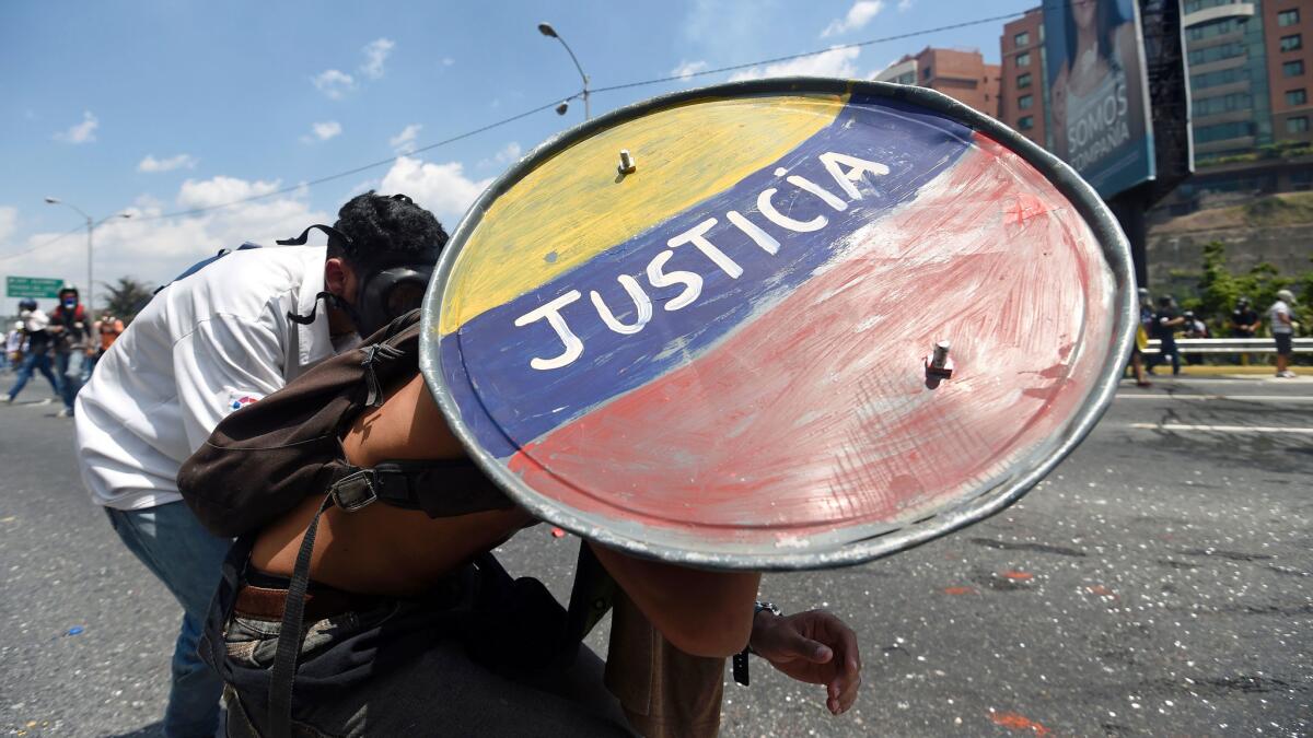 Opposition demonstrators clash with riot police during a march in Caracas on April 26, 2017. Protesters in Venezuela plan a high-risk march against President Maduro Wednesday, sparking fears of fresh violence after demonstrations that have left 26 dead in the crisis-wracked country. The placard reads "Jailed Students and Loose Delinquents" / AFP PHOTO / JUAN BARRETOJUAN BARRETO/AFP/Getty Images ** OUTS - ELSENT, FPG, CM - OUTS * NM, PH, VA if sourced by CT, LA or MoD **