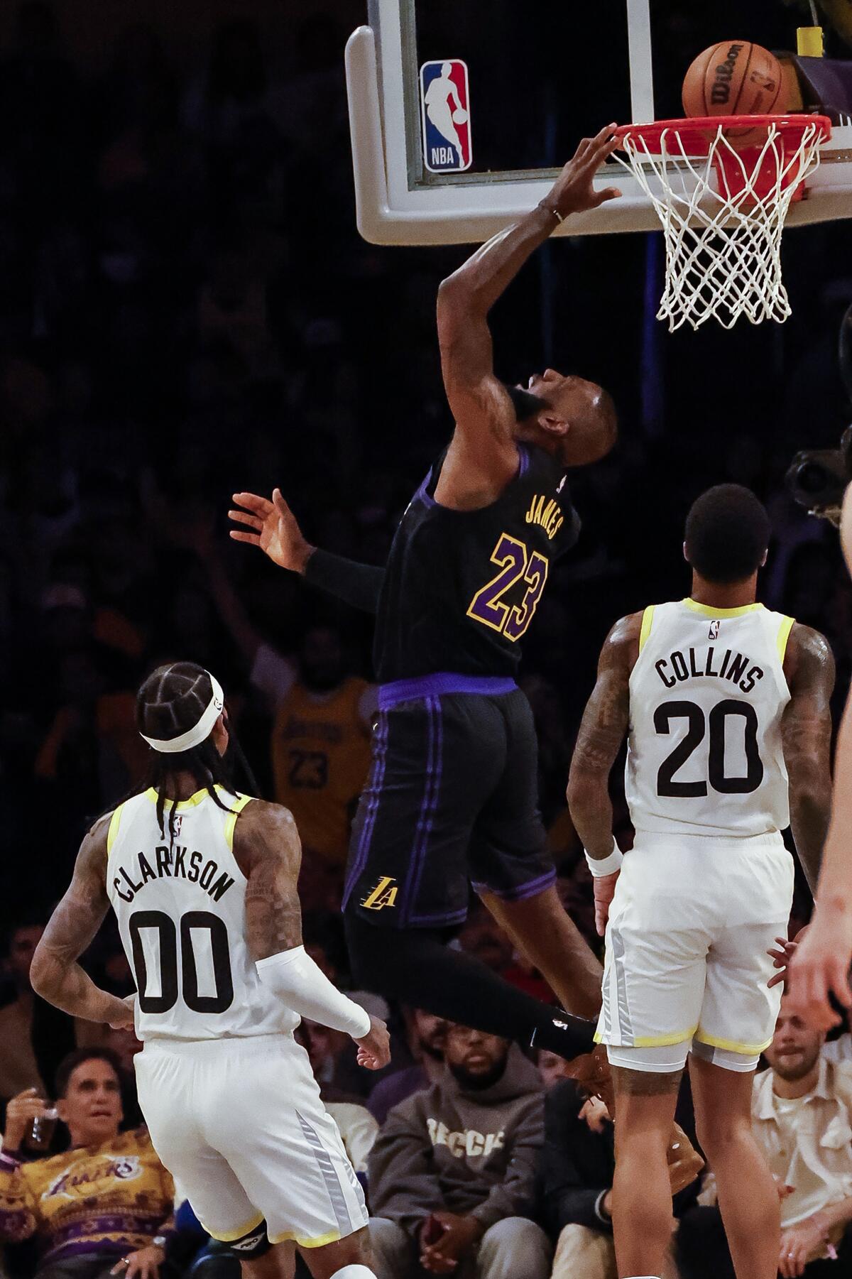 Laker LeBron James lays in a bucket in front of the the Jazz's Jordan Clarkson and John Collins