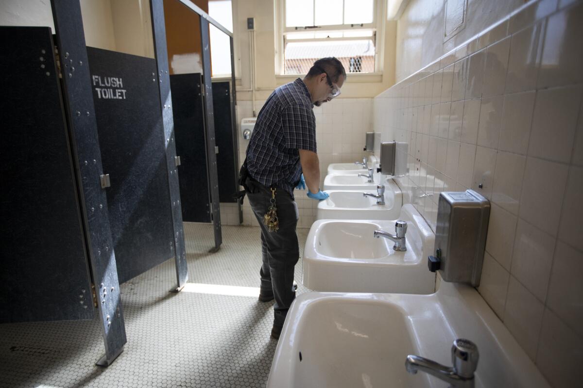 Martin Nevarez cleans a bathroom at Burroughs Middle School in Los Angeles on Tuesday.