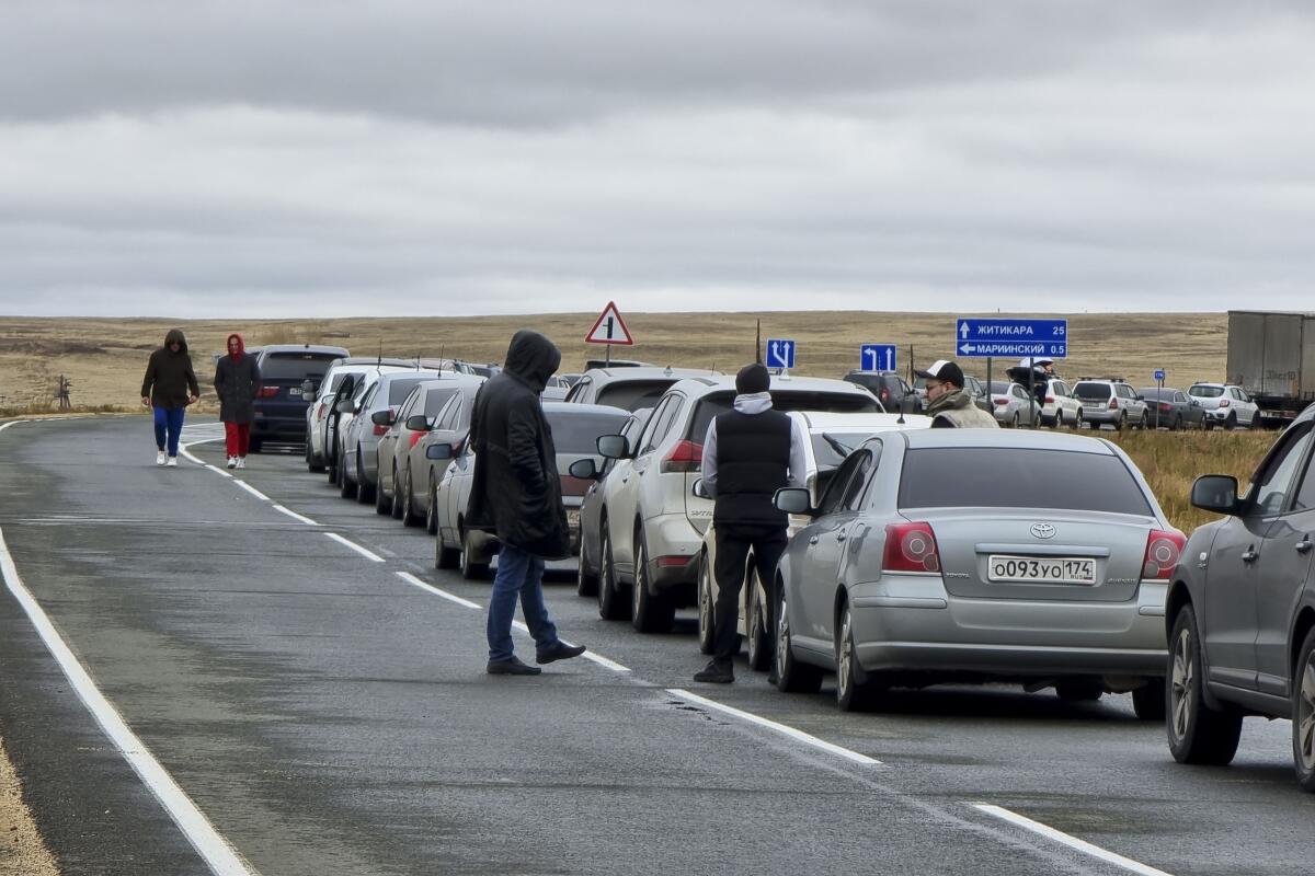 People walk next to their cars queuing to cross the border into Kazakhstan.