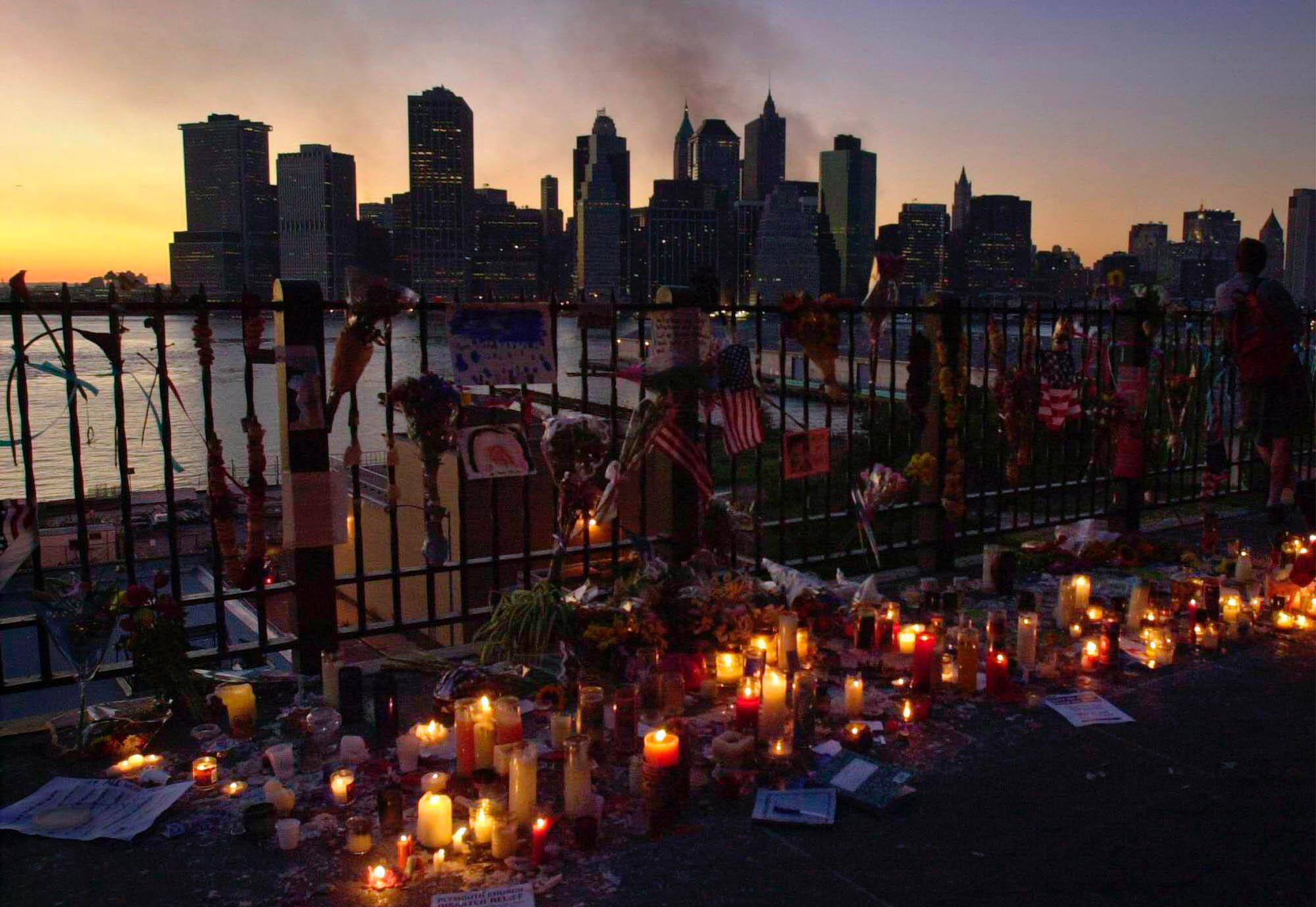 Candles flicker near a fence beside a river