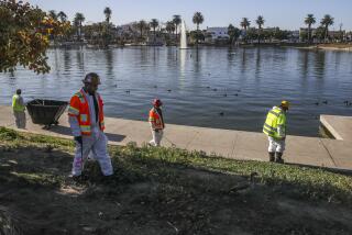 Los Angeles, CA - October 16: South side of MacArthur Park is closed to public for an extensive clean-up and major renovation. Clean-up crew busy in collecting trash and sanitizing the MacArthur Park on Saturday, Oct. 16, 2021 in Los Angeles, CA. (Irfan Khan / Los Angeles Times)
