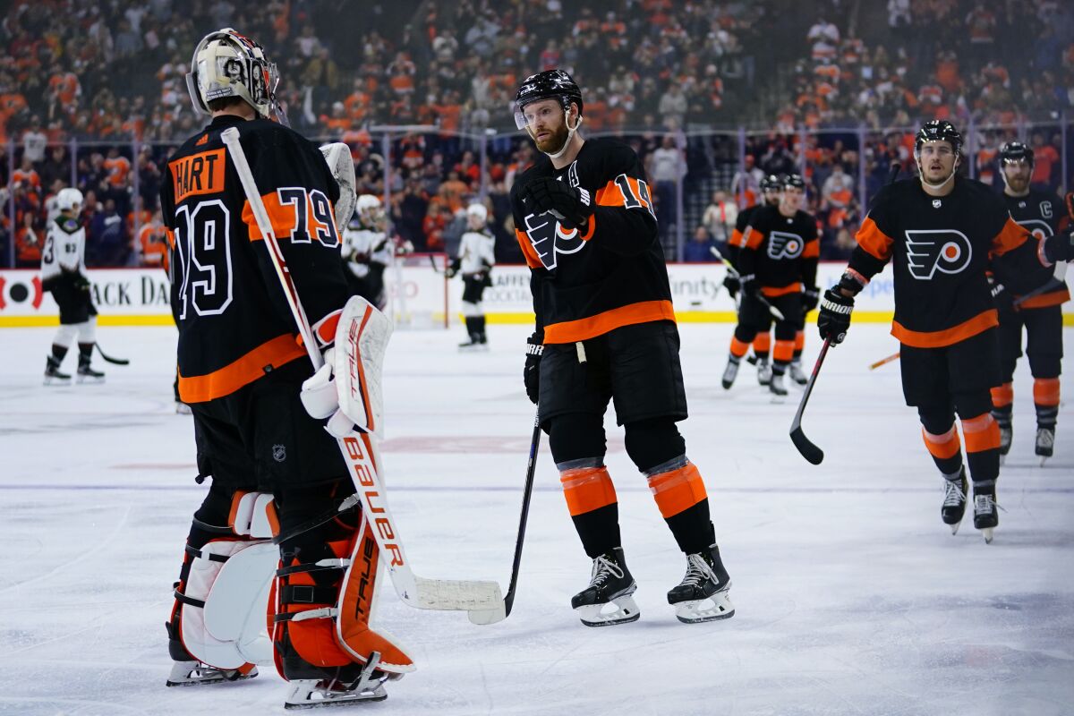 Philadelphia Flyers' Sean Couturier (14) celebrates with Carter Hart (79) after scoring a goal during the third period of an NHL hockey game against the Arizona Coyotes, Tuesday, Nov. 2, 2021, in Philadelphia. (AP Photo/Matt Slocum)
