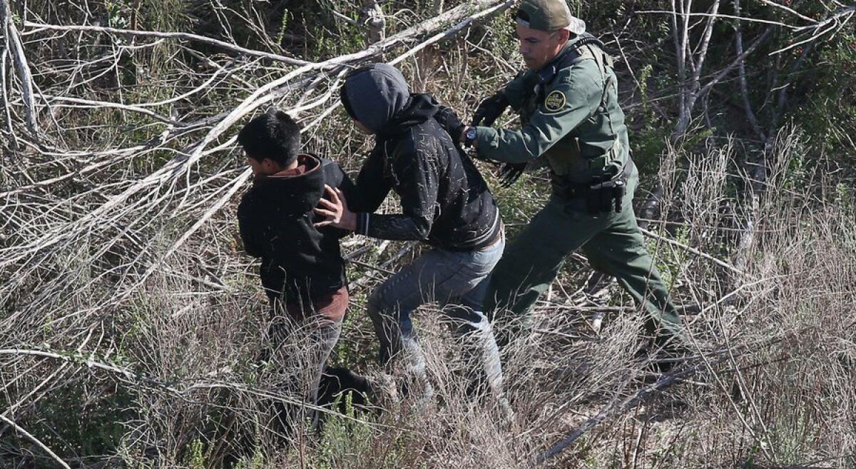 Un agente de la Patrulla Fronteriza guía a dos menores detenidos en la frontera cerca de La Grulla, Texas.