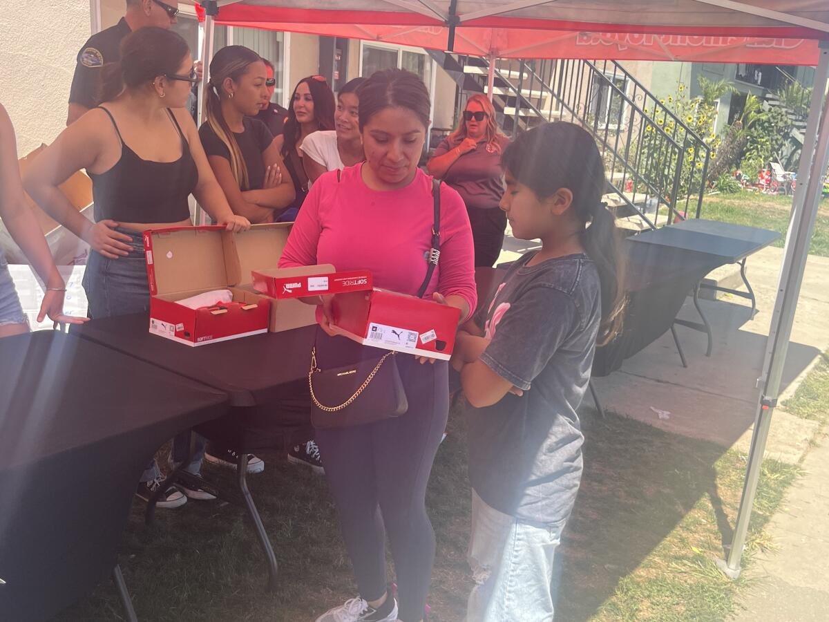 Ana Ortiz of Midway City picks up a pair of shoes for her daughter Alexandra, right, at Friday's event.