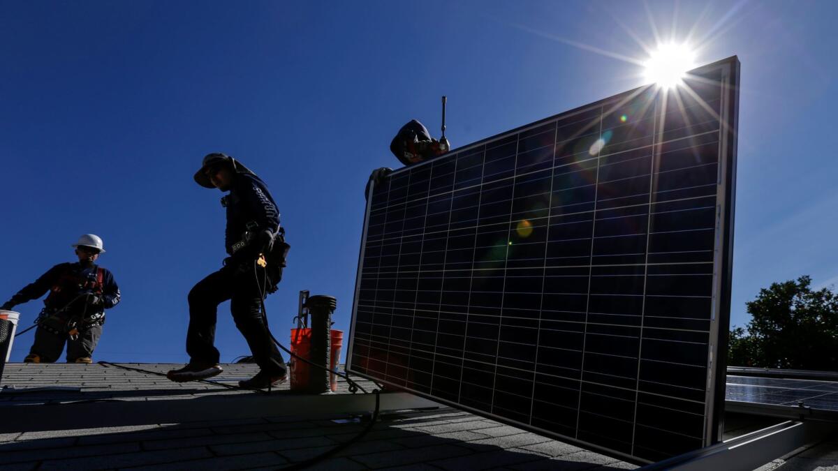 Workers install solar panels on a roof. Two new bills will boost protections for consumers taking out PACE loans that fund solar panel installations and other home improvements.