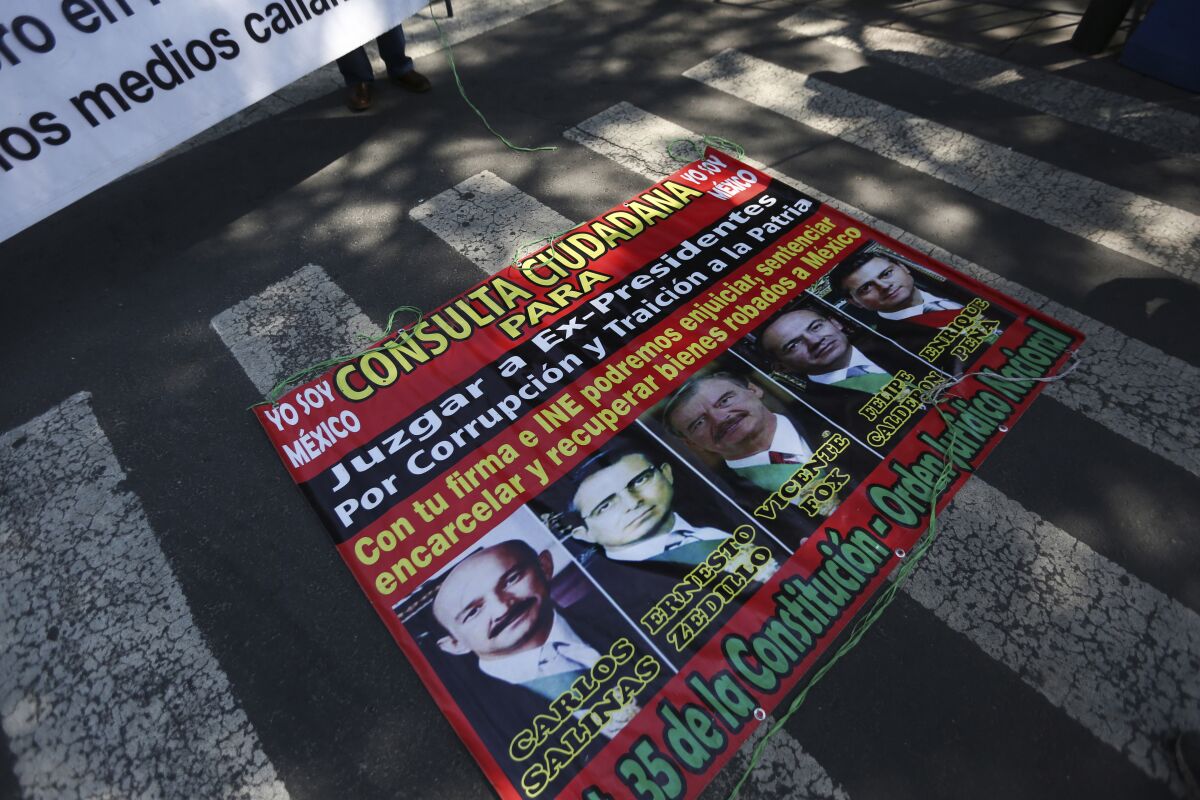 A poster with former Mexican presidents lays on the ground outside the Supreme Court during a demonstration by supporters of Mexico's current President Andres Manuel Lopez Obrador in Mexico City, Thursday, Oct. 1, 2020. The court is scheduled to decide whether the president's proposal to hold a popular vote on whether or not to pursue former presidents on corruption charges stands up to scrutiny. (AP Photo/Fernando Llano)