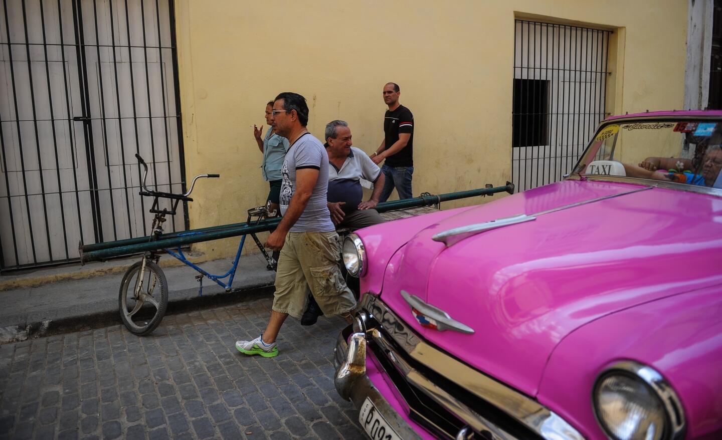 A man walks next to a U.S.-made vintage car in Havana on March 17, 2016.