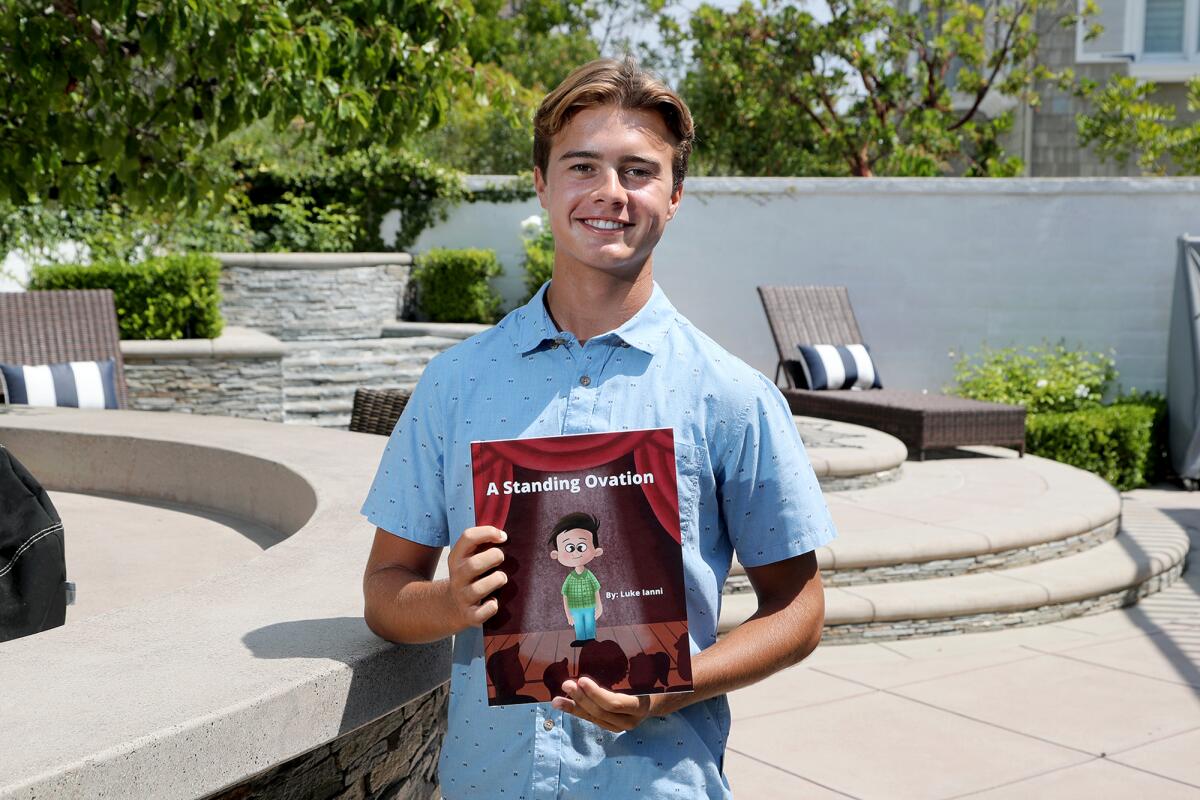 Luke Ianni, 17, holds up his self-published children's book, "A Standing Ovation," in Newport Beach on Wednesday.