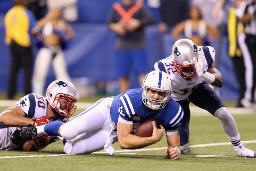 Indianapolis quarterback Andrew Luck is taken down by New England's Rob Ninkovich, left, on Nov. 16.