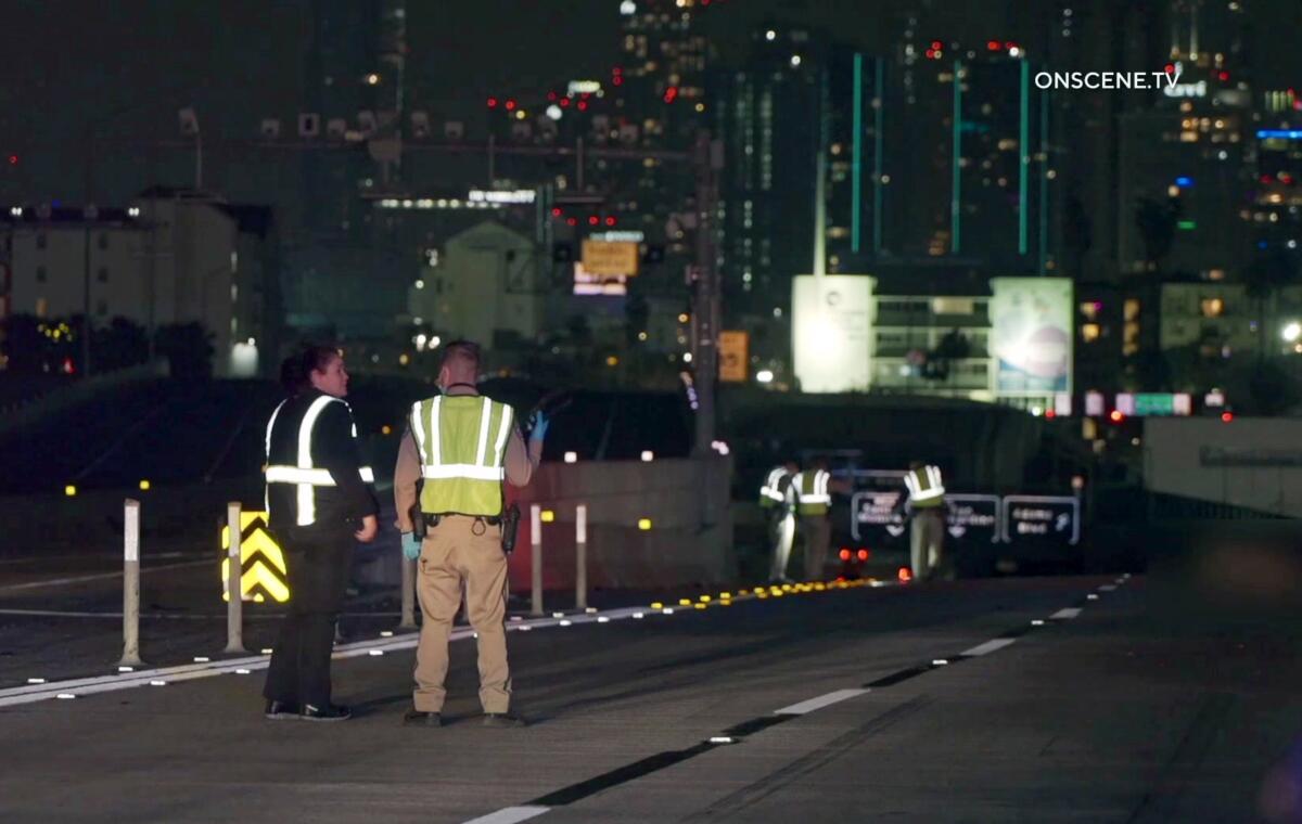 Men in emergency vests stand on a freeway near dividers