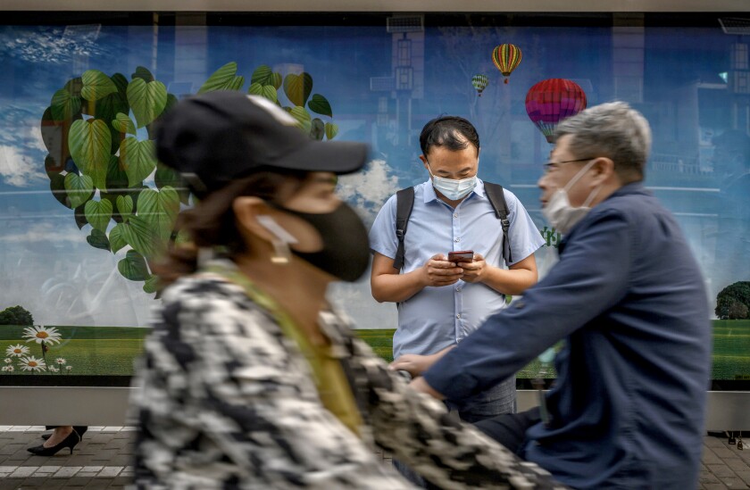 A Chinese commuter looks at his mobile phone as he waits at a bus stop