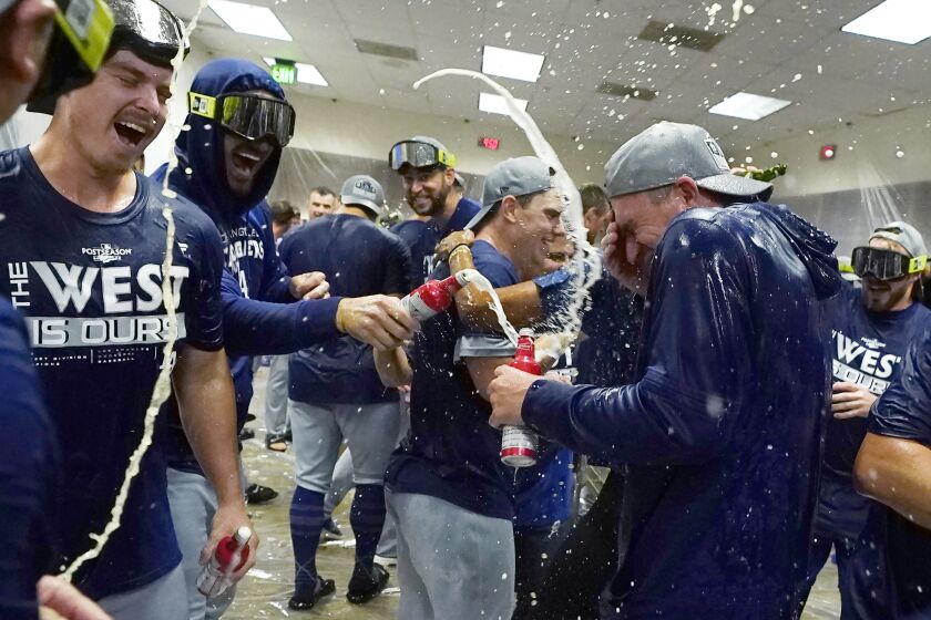 Los Angeles Dodgers celebrate in the locker room after a 4-0 win in a baseball game against the Arizona Diamondbacks in Phoenix, Tuesday, Sept. 13, 2022. The Dodgers clinched the National League West. (AP Photo/Ross D. Franklin)