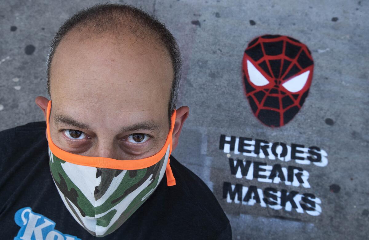 Neal Brandenburg poses in front of a Spider-Man mask that he painted.