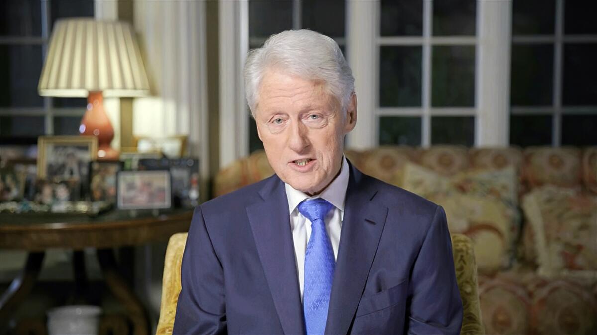 Former President Clinton is shown seated in a living room.