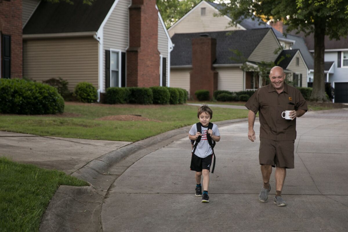 Jason Rochester walks his son, Ashton, 6, to the school bus stop in Roswell, Ga.