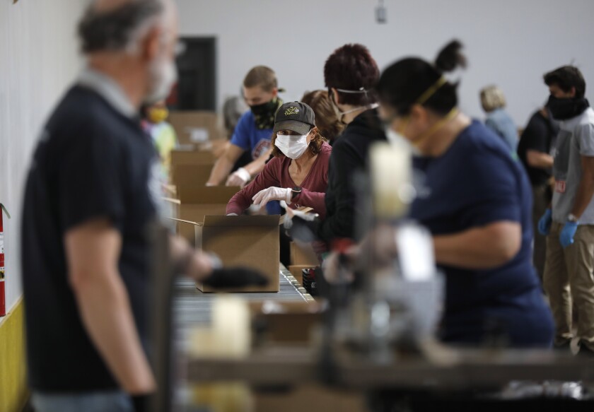 Volunteers put together boxes of food for people at the Jacobs & Cushman San Diego Food Bank on April 14, 2020.