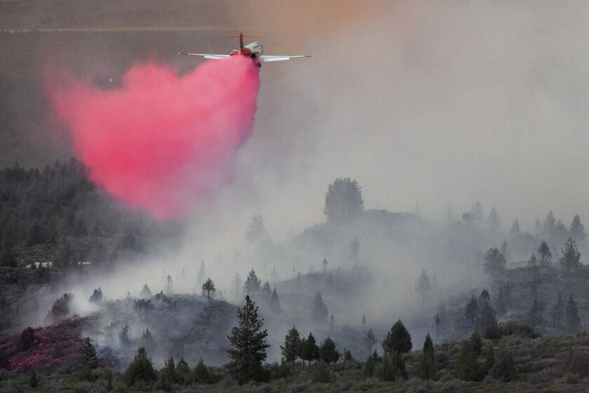 In this Monday, June 28, 2021, photo Tanker 105, an MD-87 aircraft operated by Erickson Aero Tanker of Hillsboro, Ore., drops retardant in an effort to stop the advancing Lava Fire northeast of Weed, Calif. A wildfire that has put thousands of people under evacuation orders in Northern California grew substantially but firefighters had some success against the flames, authorities said Wednesday, June 30. Burning in the shadow of the towering Mount Shasta volcano, the Lava Fire was ignited by lightning last week. (Scott Stoddard/Grants Pass Daily Courier via AP)