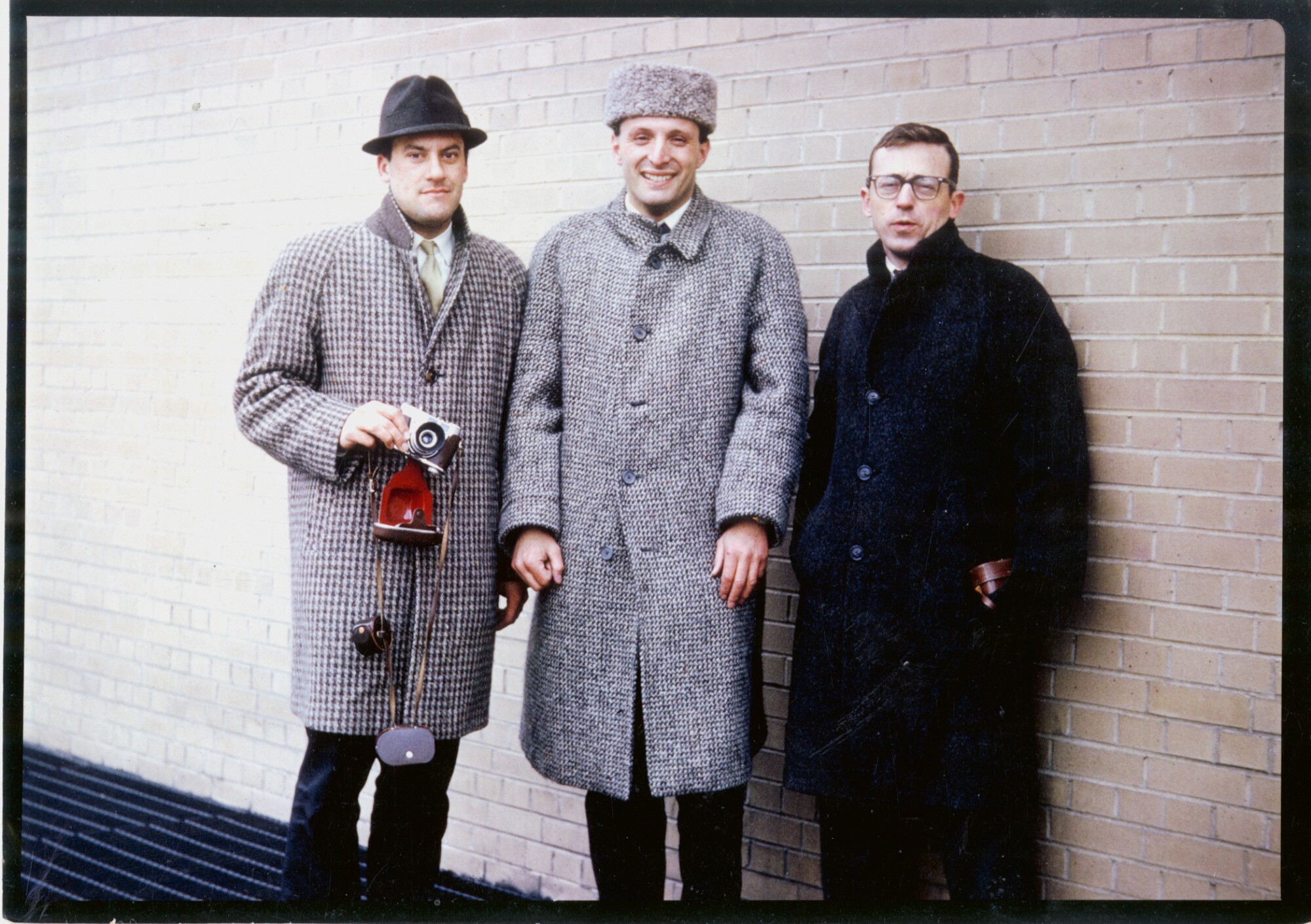 Norman Foster, Richard Rogers and Carl Abbott, bundled up in wool coats stand against a brick wall.