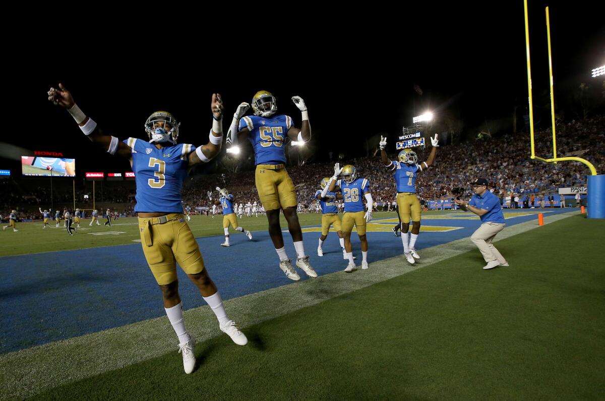 Members of the UCLA football team begin celebrating their 45-44 comeback victory over Texas A&M in the closing moments of the game Sept. 3.