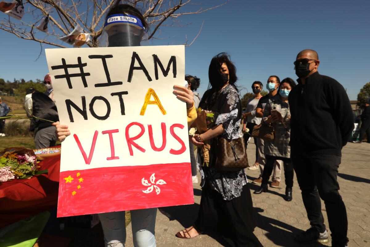 A woman holds a sign saying "I am not a virus."