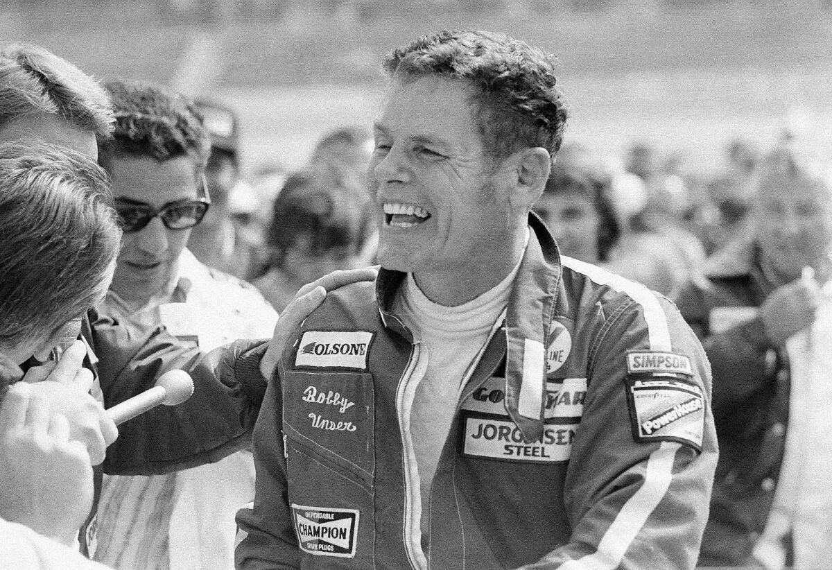 FILE - Bobby Unser is a happy man as he accepts congratulations in the winner's circle for his triumph in the California 500 at Ontario Motor Speedway in Ontario, Calif., March 11, 1974. He beat his brother, Al, by a half second to win $70,250. Al Unser, one of only four drivers to win the Indianapolis 500 a record four times, died Thursday, Dec. 9, 2021, following years of health issues. He was 82. (AP Photo, File)